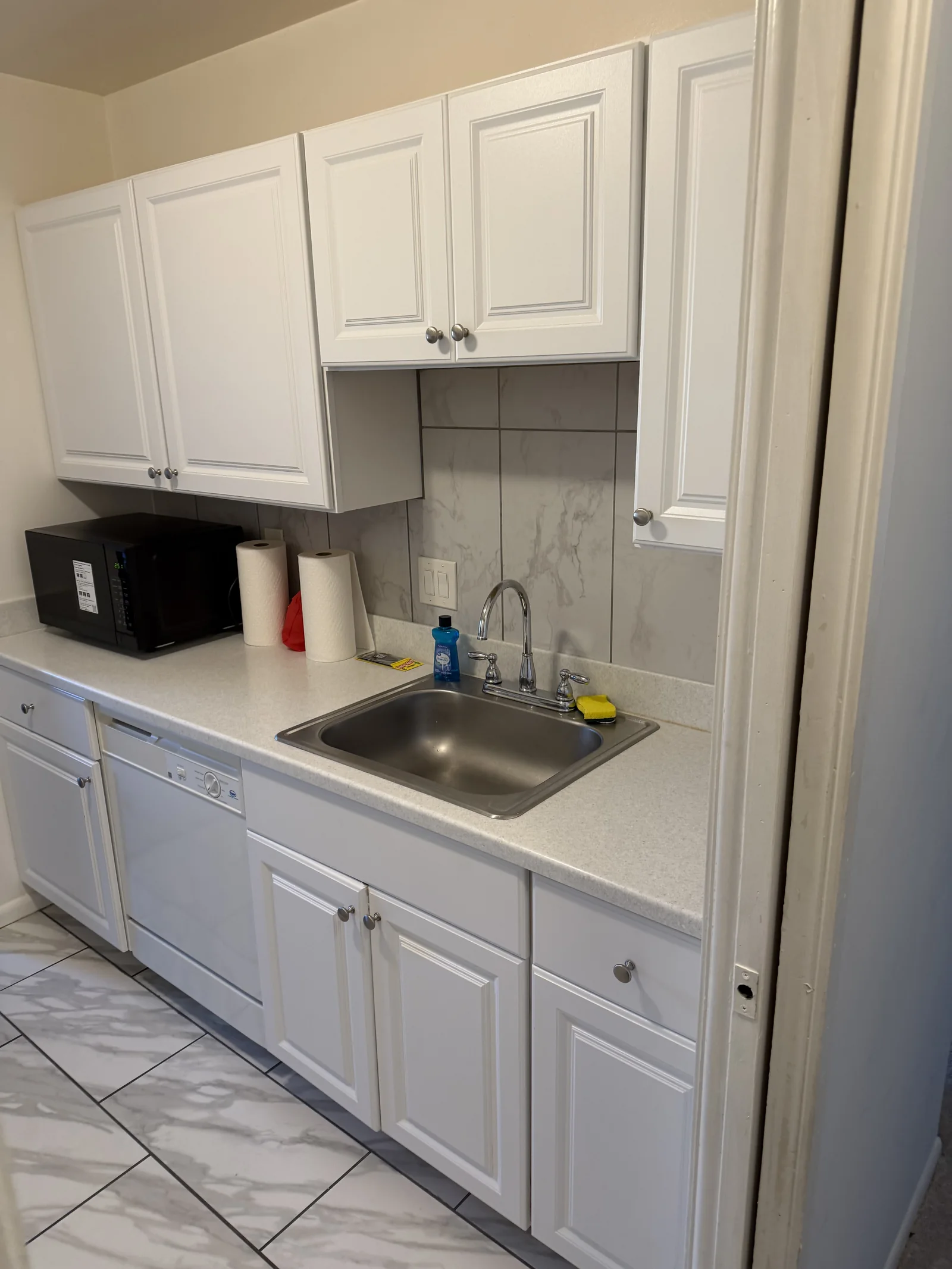 Client-provided photo of a clean white kitchen and sink area