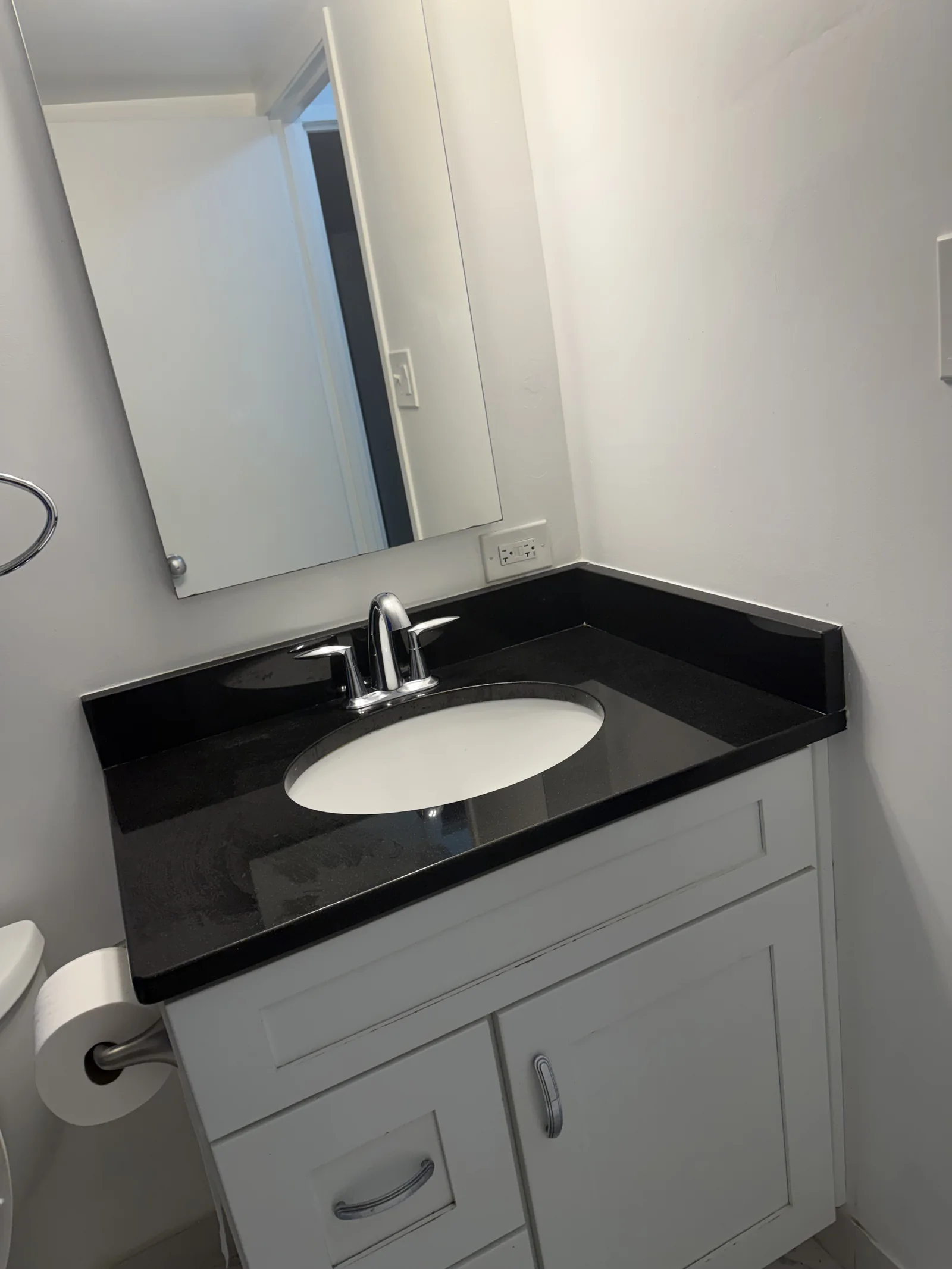 Client-provided photo of a clean black countertop and white powder-room vanity