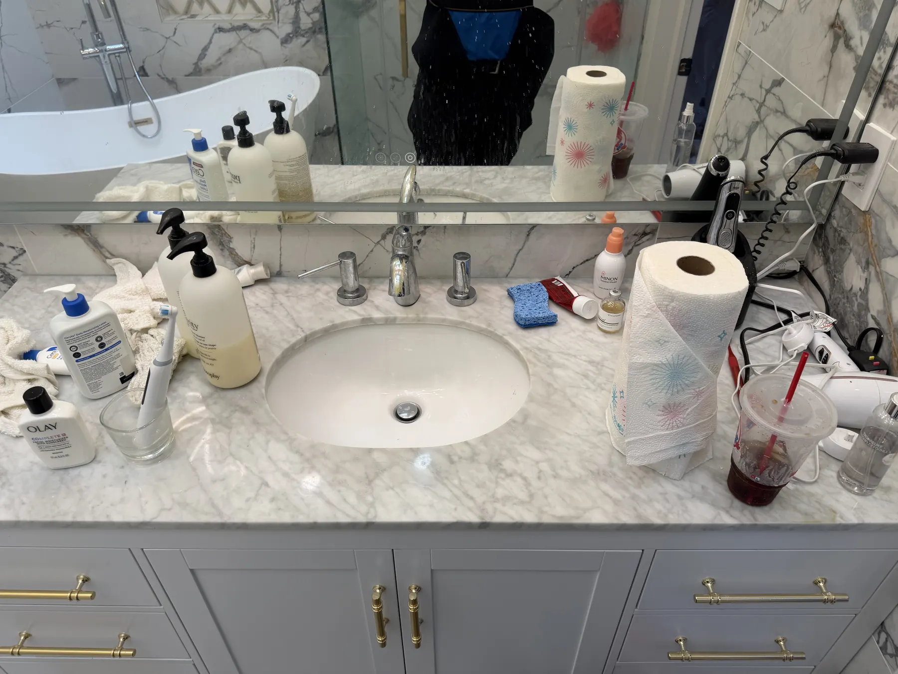 Client-provided before photo showing personal items across a bathroom vanity